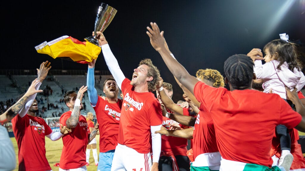 Phoenix Rising's Emil Cuello lifts the Western Conference Trophy.