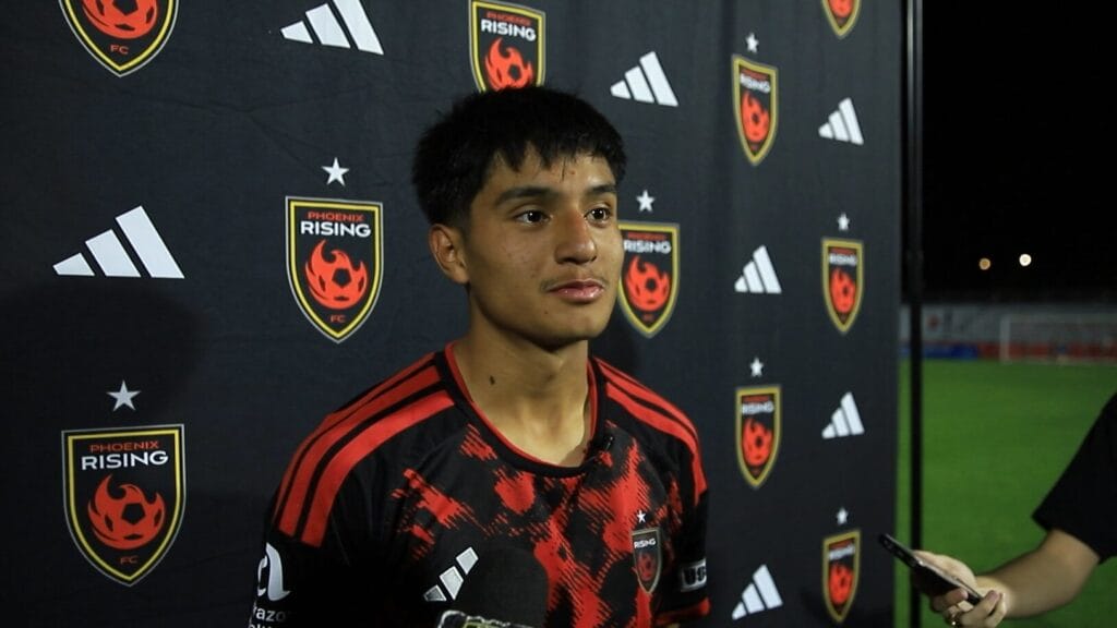 Rising forward Tony Capetillo stands in front of the press conference backdrop
