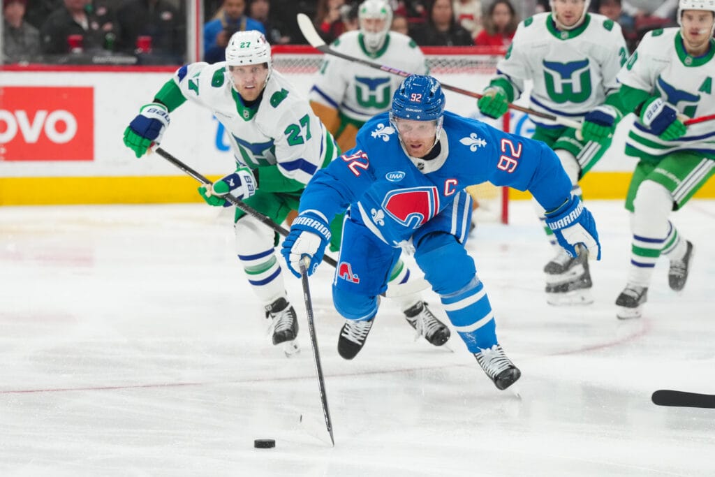 Colorado Avalanche left wing Gabriel Landeskog (92) skates with the puck past Carolina Hurricanes left wing Nikolaj Ehlers (27) during the first period at Lenovo Center. Mandatory Credit: James Guillory-Imagn Images