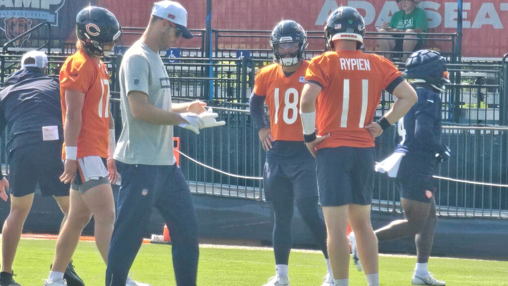 Bears QBs Tyson Bagent, Caleb Williams, and Brett Rypien stand on the practice field at Halas Hall.