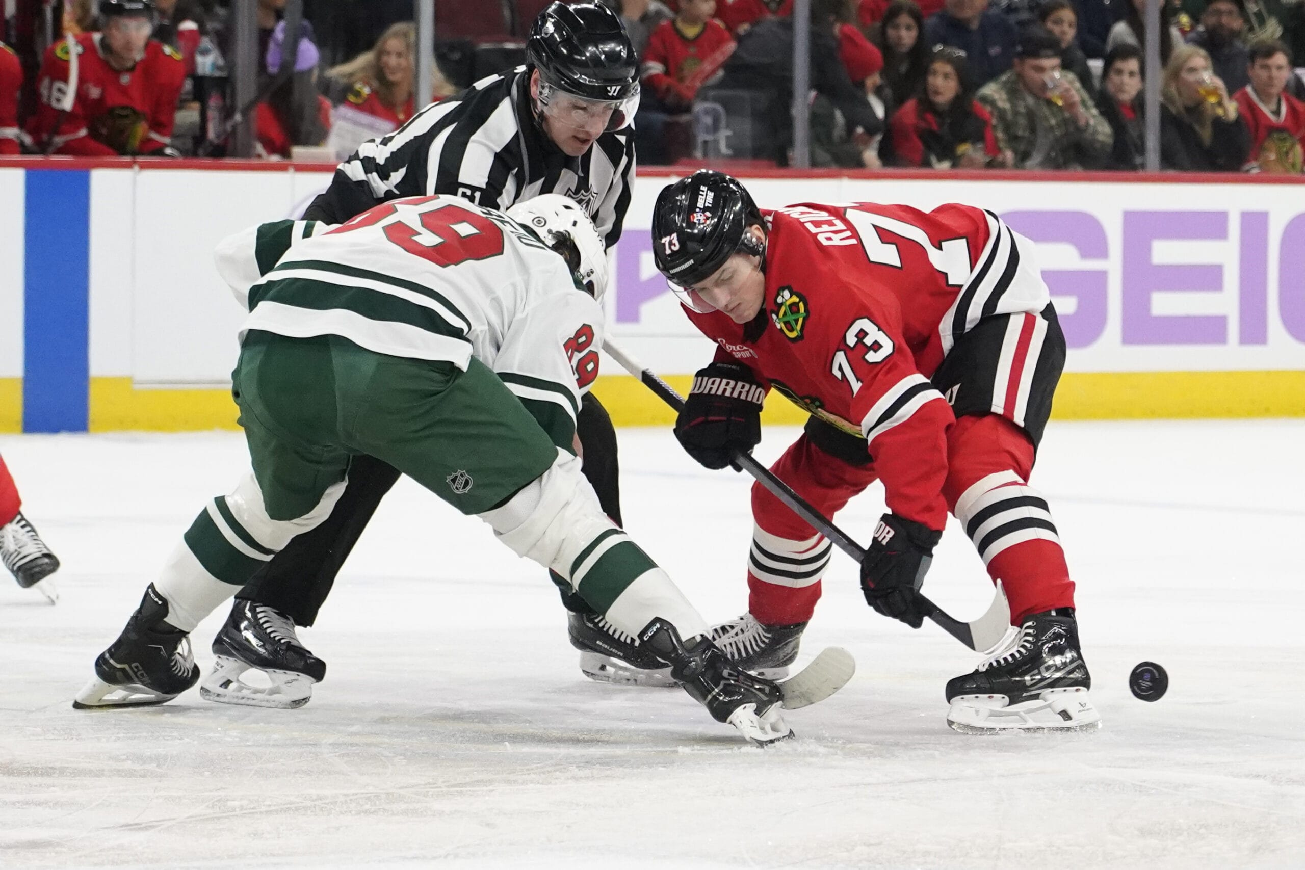 Jan 26, 2025; Chicago, Illinois, USA; Minnesota Wild center Frederick Gaudreau (89) and Chicago Blackhawks left wing Lukas Reichel (73) face-off during the first period at United Center.