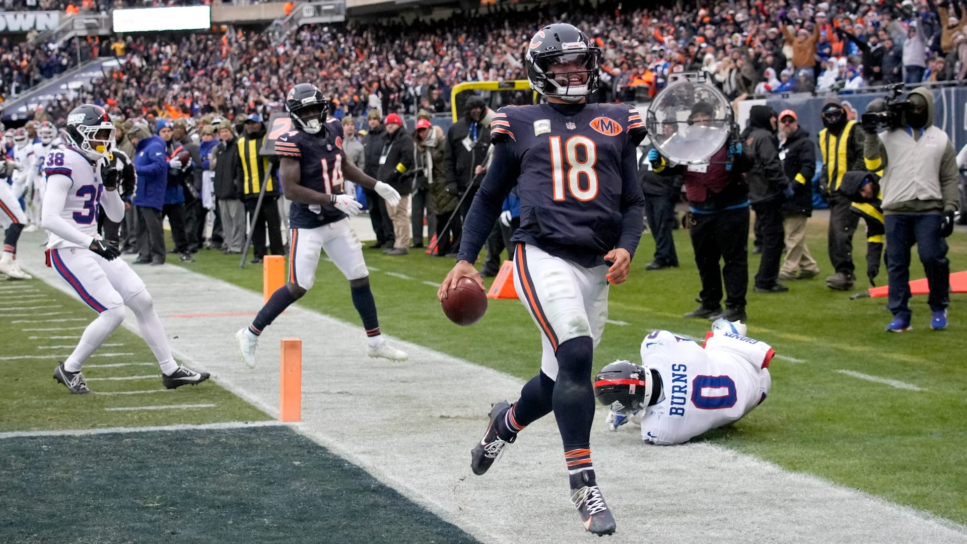 Chicago Bears quarterback Caleb Williams (18) scores the game-winning touchdown against New York Giants linebacker Brian Burns (0) during the fourth quarter at Soldier Field. Mandatory Credit: David Banks-Imagn Images