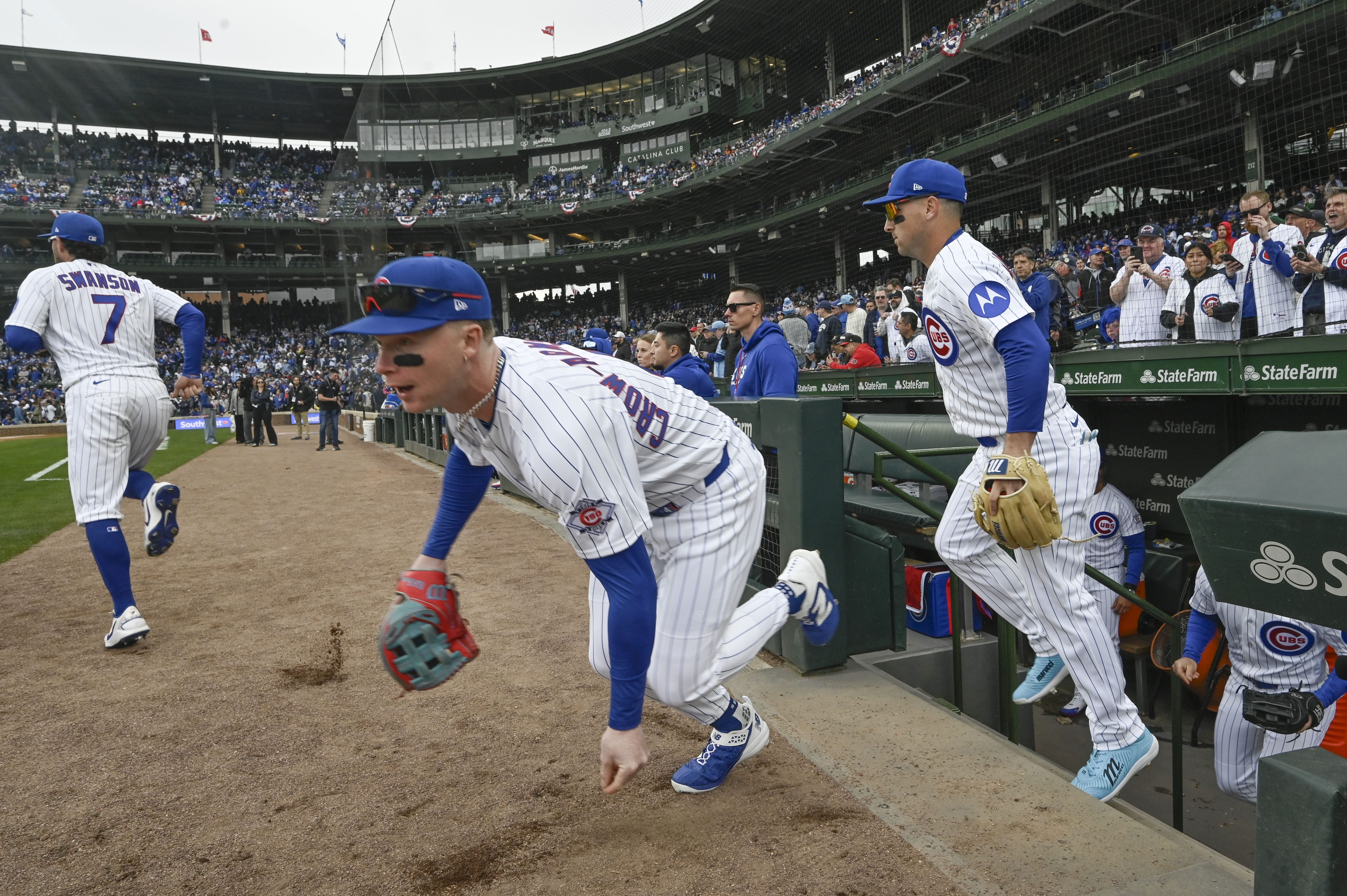 Mar 26, 2026; Chicago, Illinois, USA; Chicago Cubs center fielder Pete Crow-Armstrong (4) grabs dirt as he enters the field with teammates for an Opening Day game against the Washington Nationals at Wrigley Field.