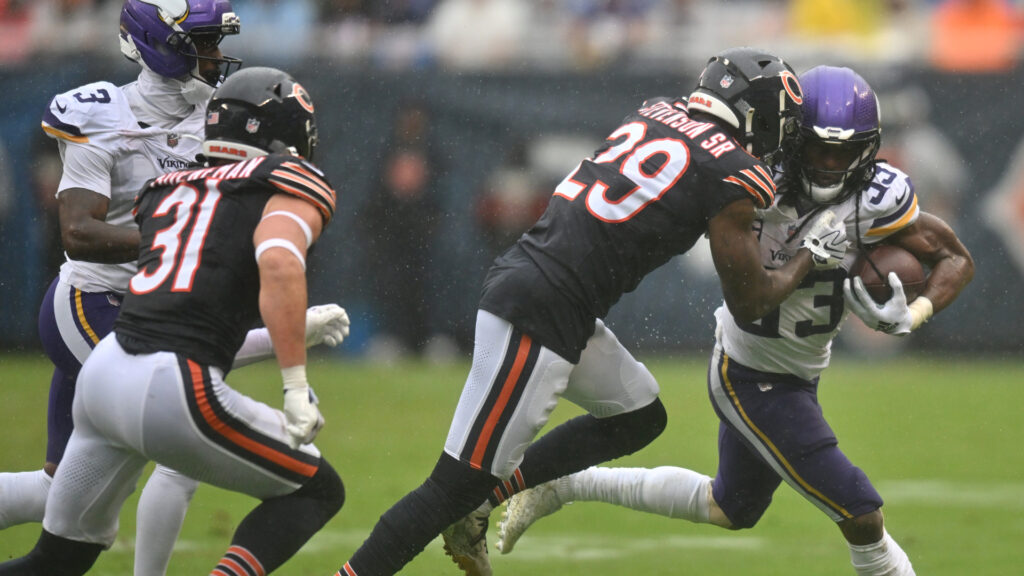 Sep 20, 2026; Chicago, Illinois, USA; Minnesota Vikings running back Aaron Jones Sr. (33) runs the ball against Chicago Bears cornerback Tyrique Stevenson (29) and safety Dillon Thieneman (31) during the first half at Soldier Field. Mandatory Credit: Patrick Gorski-Imagn Images