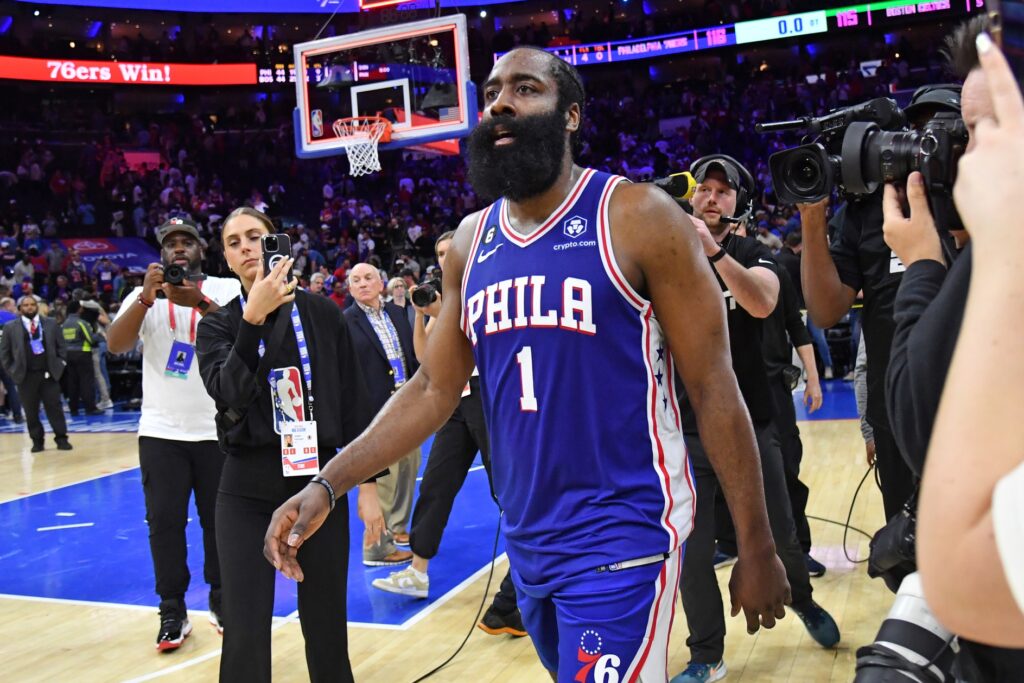 James Harden walking amongst photographers at a Sixers game.