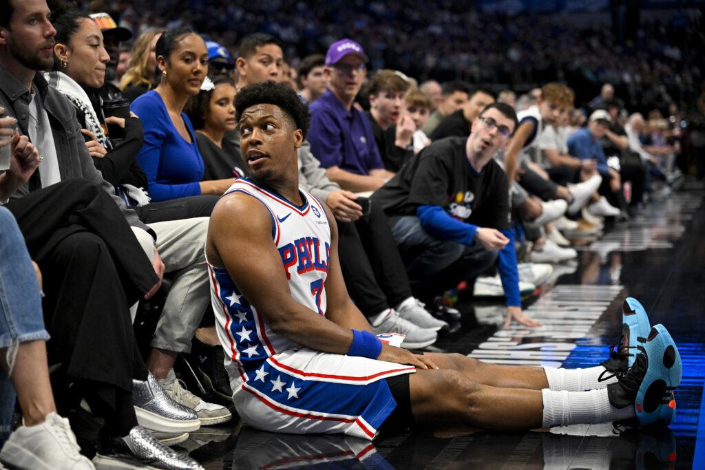 Kyle Lowry sitting with Mavericks fans on the sideline.