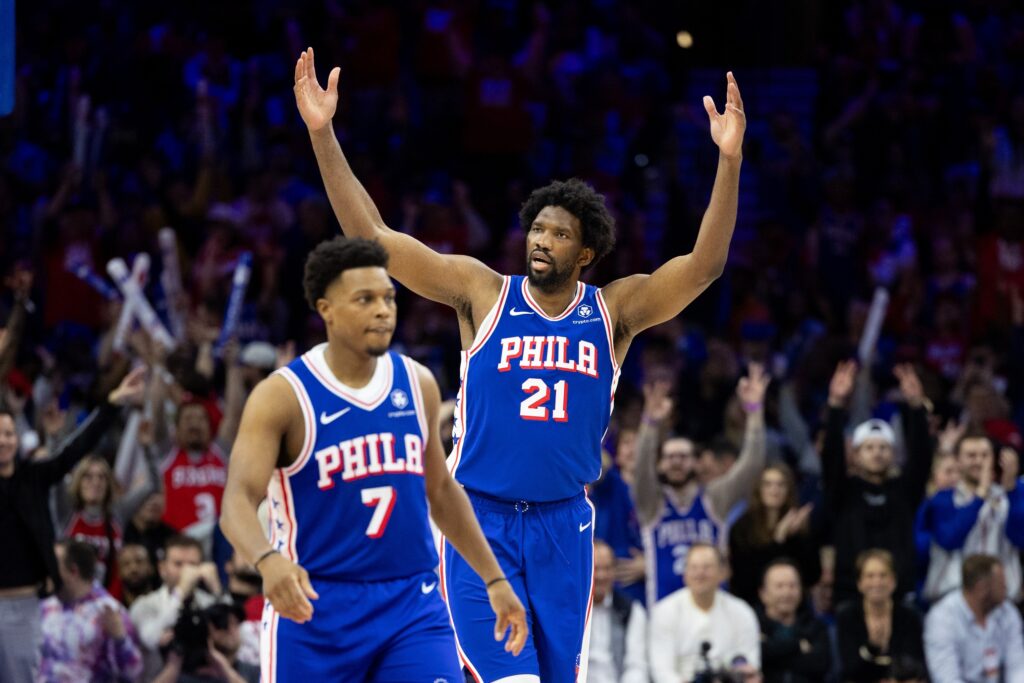 Joel Embiid egging on the crowd while standing behind Kyle Lowry.