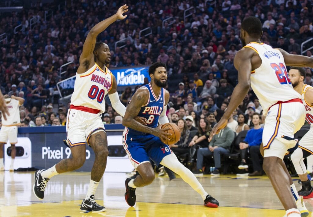 Paul George between two Warriors defenders